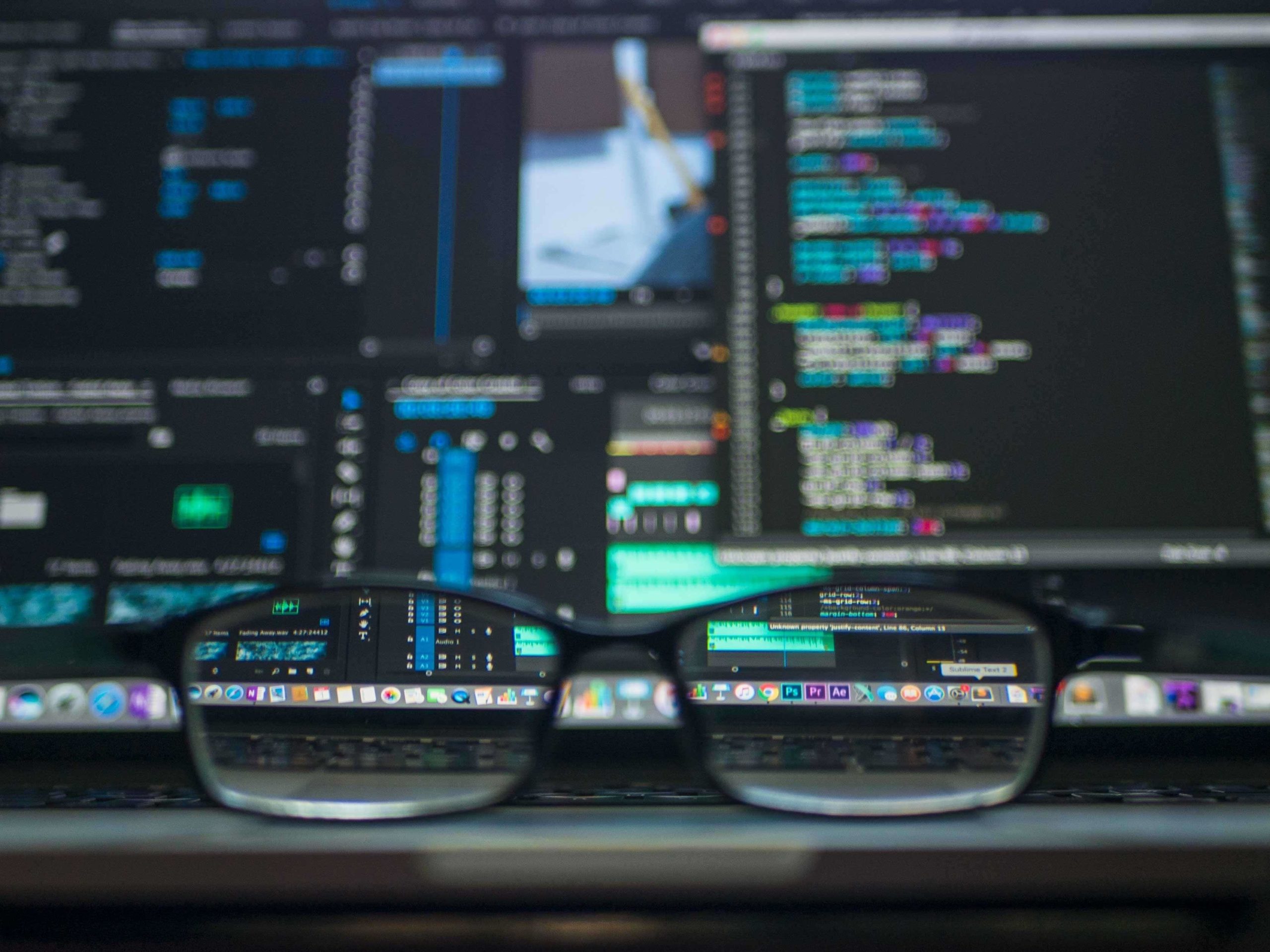 Glasses sitting in front of computer screens displaying code